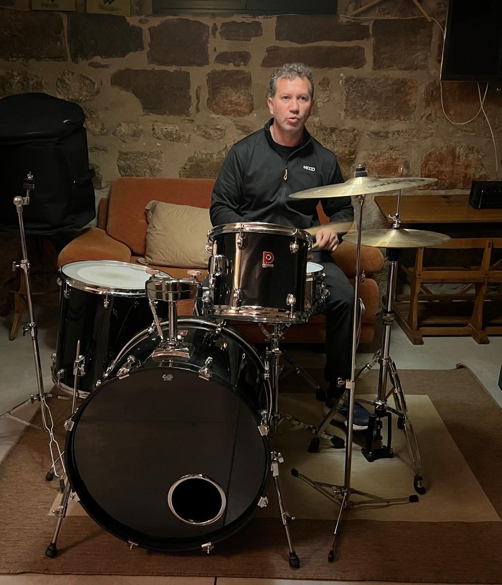 Alberto tocando la batería bajo luces violetas